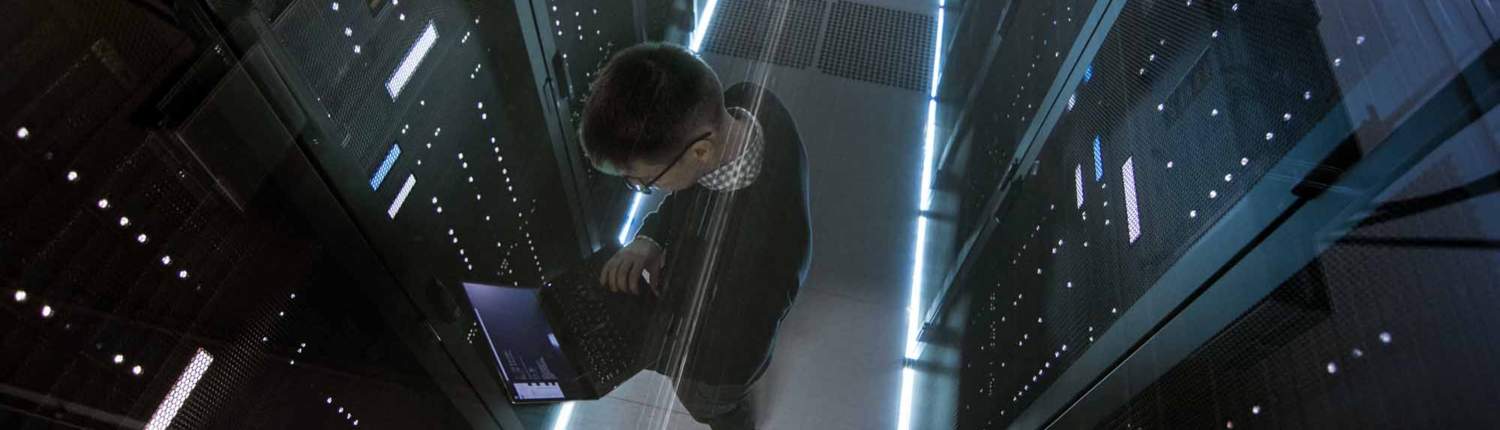 man working on a laptop in a data center