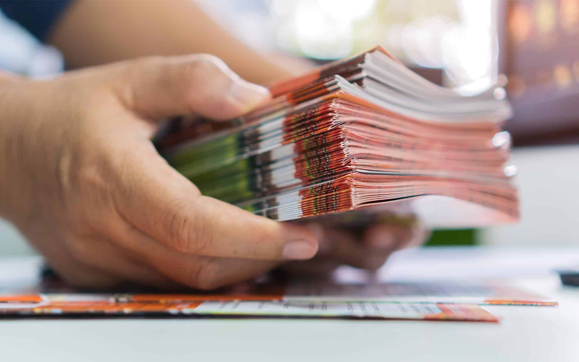 Side view of someone holding a stack of brochures