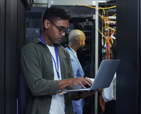 Cropped shot of two male IT support agents working together in a dark network server room
