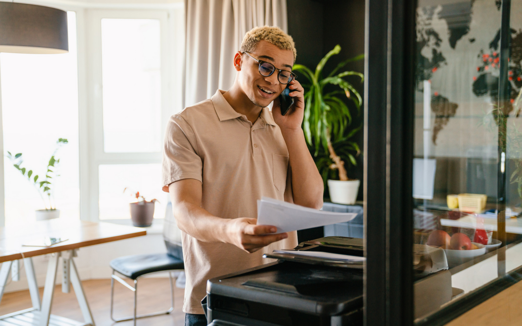 Smiling Man Using Phone And Printer