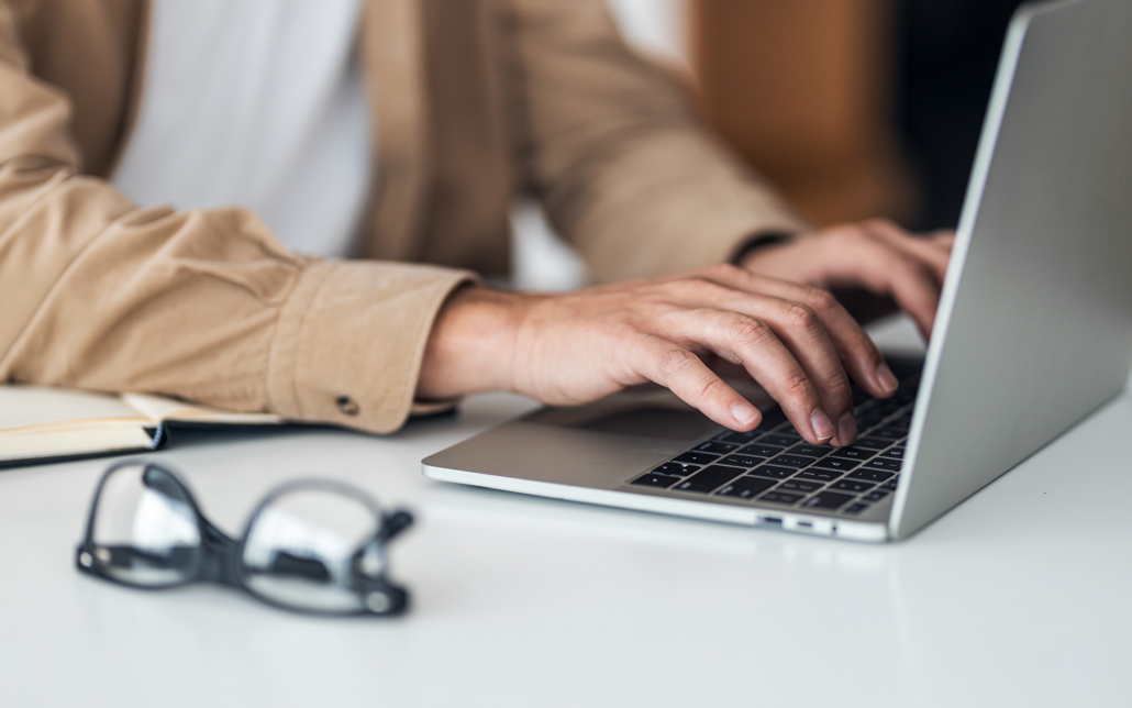 View Of Hands Typing On Laptop Keyboard